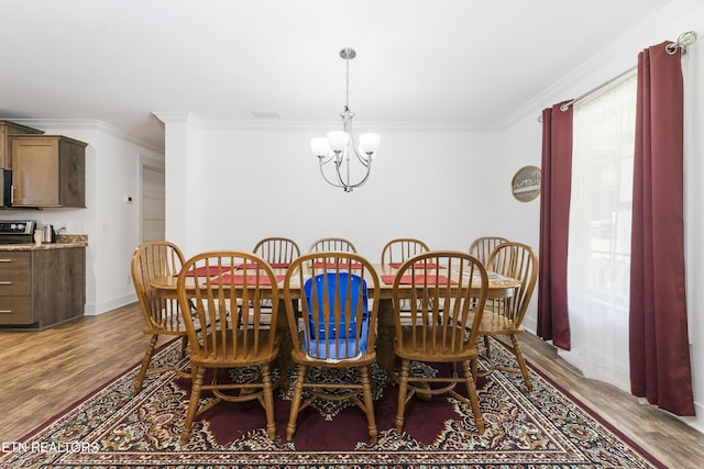 dining area with wood-type flooring, crown molding, and an inviting chandelier