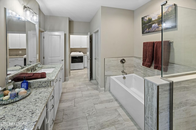 bathroom featuring a washtub, vanity, and washer / clothes dryer