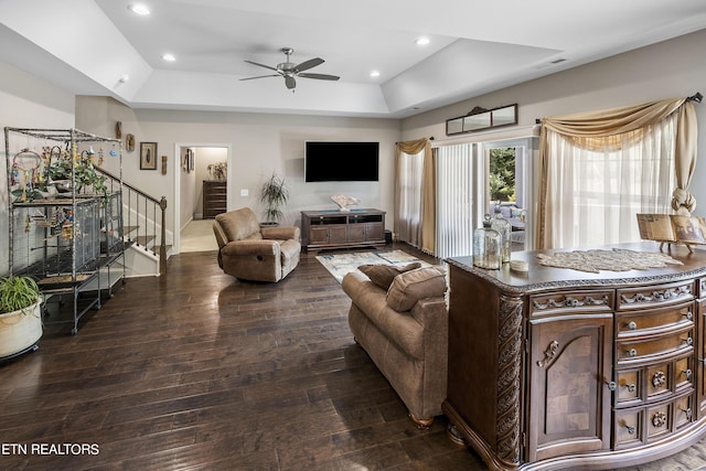 living room with hardwood / wood-style flooring, ceiling fan, and a raised ceiling