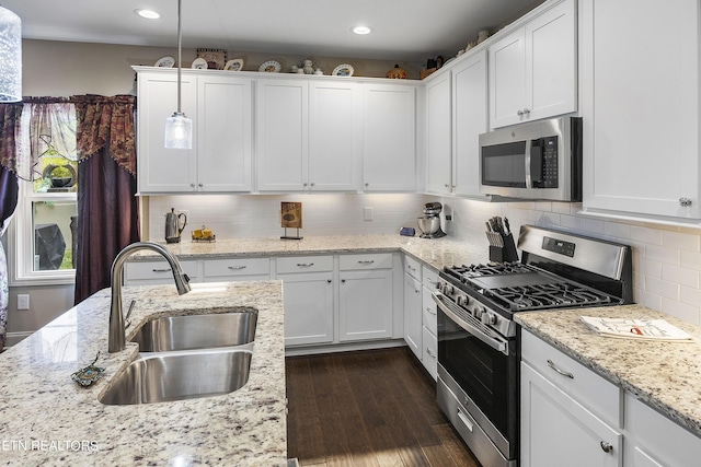 kitchen featuring white cabinetry, stainless steel appliances, tasteful backsplash, sink, and hanging light fixtures