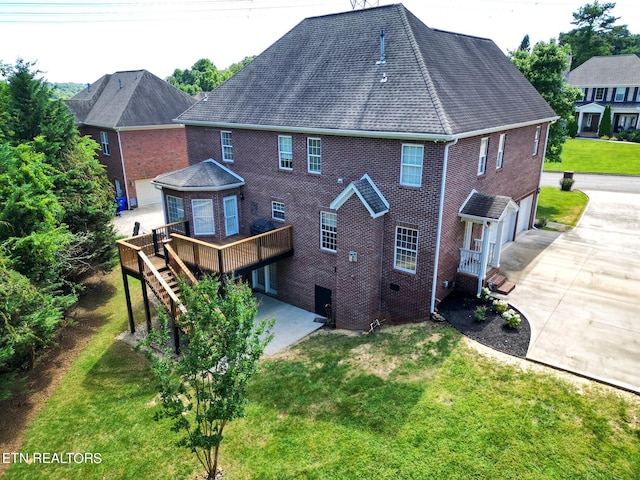 back of property with a garage, a yard, and a deck