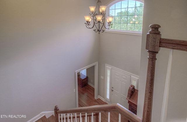 stairway with wood-type flooring and a chandelier