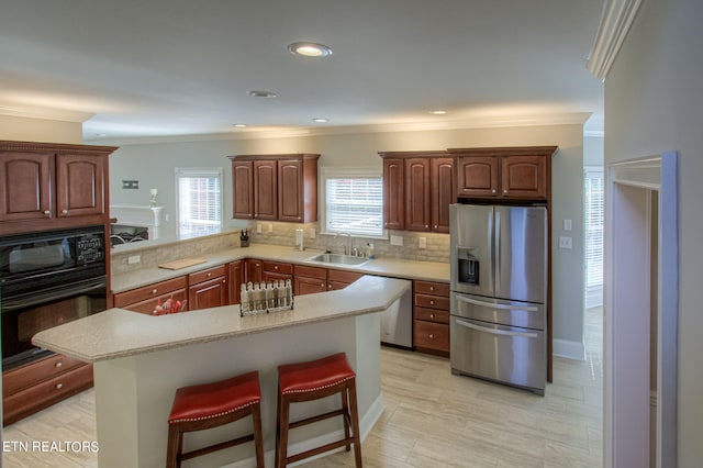 kitchen featuring sink, black appliances, a kitchen bar, decorative backsplash, and kitchen peninsula