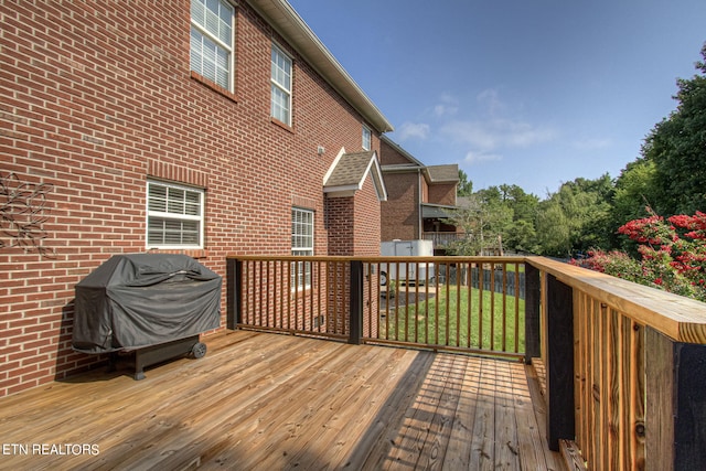 wooden terrace featuring a grill and a yard