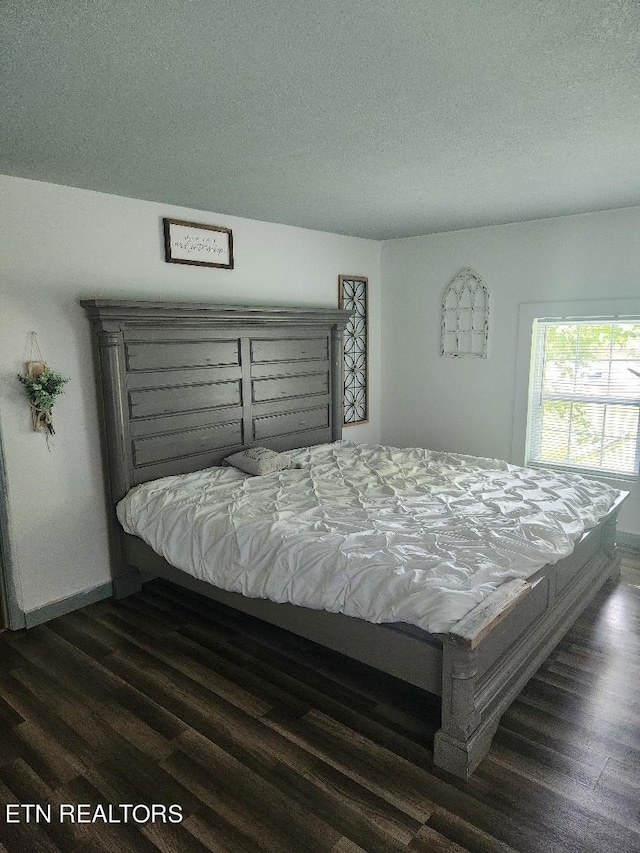 bedroom with a textured ceiling and dark wood-type flooring