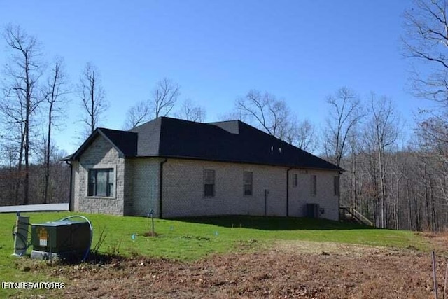 view of side of home with a yard and central AC