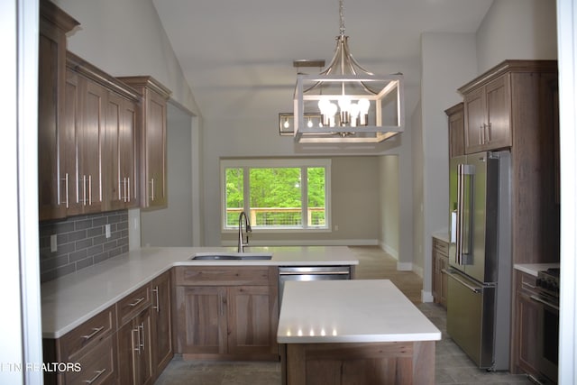 kitchen with sink, tasteful backsplash, a chandelier, decorative light fixtures, and high quality fridge