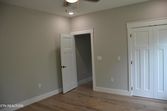 unfurnished bedroom featuring a closet, light hardwood / wood-style flooring, and ceiling fan