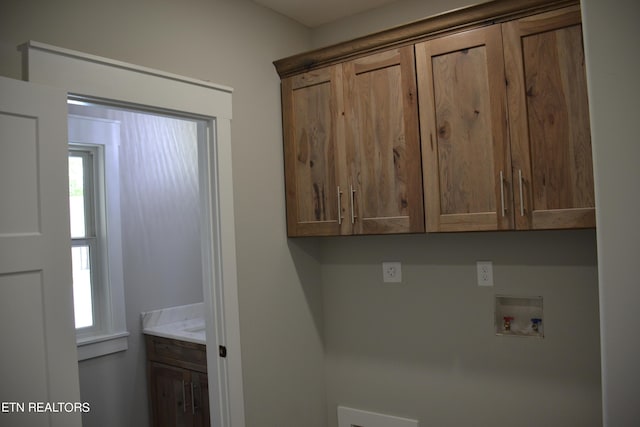 laundry area with a wealth of natural light, hookup for a washing machine, and cabinets