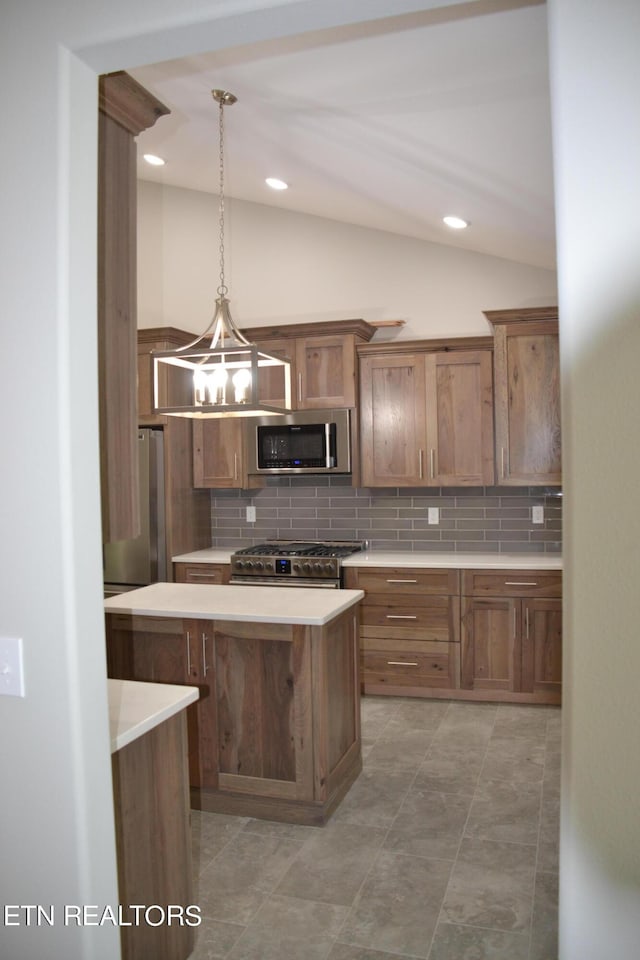 kitchen with pendant lighting, lofted ceiling, light tile patterned floors, tasteful backsplash, and stainless steel appliances