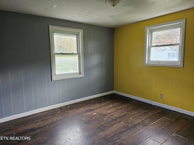 spare room with dark wood-type flooring and wooden walls