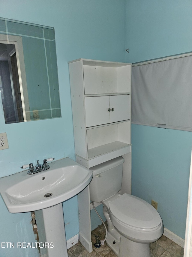 bathroom featuring toilet, tile patterned floors, and sink