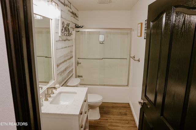 full bathroom with vanity, hardwood / wood-style floors, shower / bath combination with glass door, and toilet