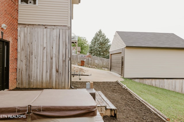 view of yard featuring a garage, an outdoor structure, and a hot tub