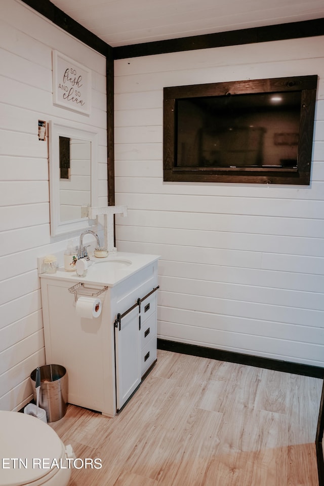 bathroom featuring vanity, hardwood / wood-style floors, toilet, and wood walls