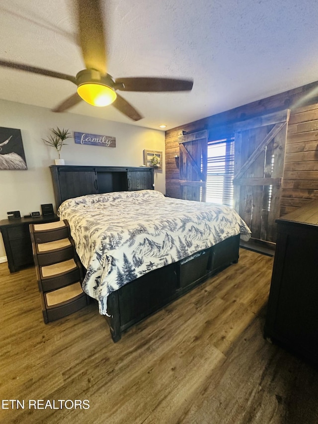 bedroom with ceiling fan, dark hardwood / wood-style flooring, and a textured ceiling