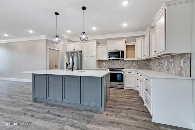 kitchen featuring white cabinets, stainless steel appliances, decorative light fixtures, and light hardwood / wood-style flooring