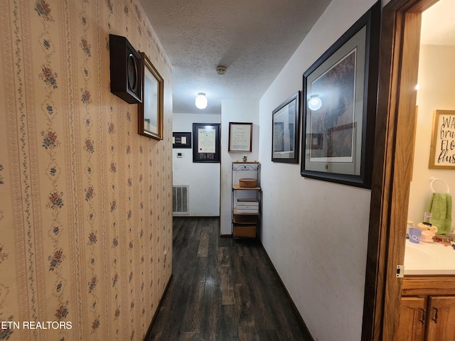 hallway with dark wood-type flooring and a textured ceiling