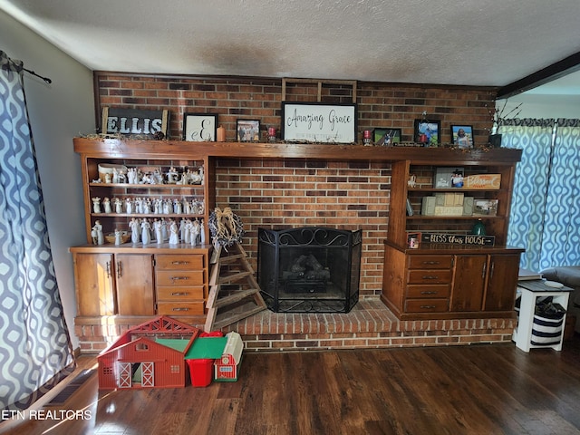 living room featuring wood-type flooring, a fireplace, brick wall, and a textured ceiling