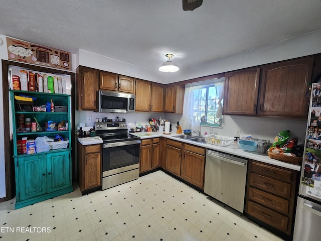 kitchen with sink, a textured ceiling, and appliances with stainless steel finishes