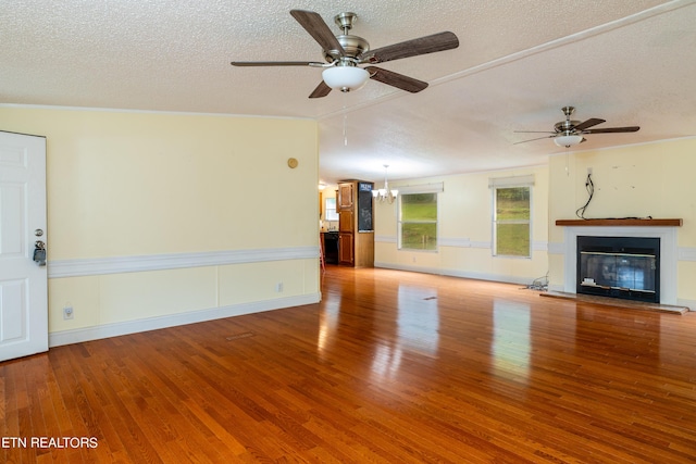 unfurnished living room featuring hardwood / wood-style flooring, ceiling fan with notable chandelier, a textured ceiling, and vaulted ceiling