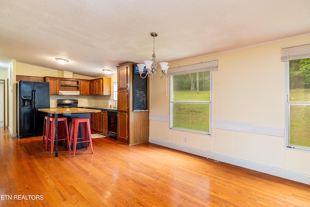 kitchen with a kitchen bar, black appliances, decorative light fixtures, an inviting chandelier, and lofted ceiling