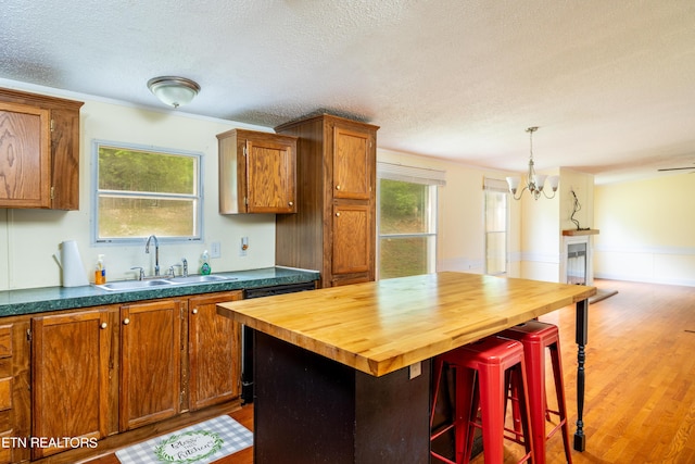 kitchen with sink, a center island, wood counters, a breakfast bar, and hardwood / wood-style flooring