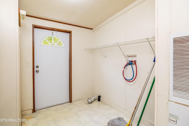 laundry room featuring hookup for a washing machine, a textured ceiling, and ornamental molding