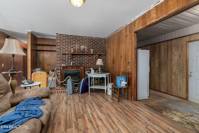 living room featuring a brick fireplace, hardwood / wood-style floors, crown molding, and wood walls