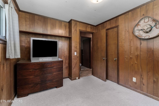 bedroom with crown molding, light colored carpet, and wood walls