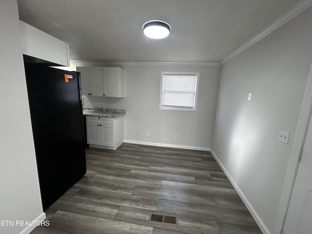 kitchen with black fridge, white cabinets, dark hardwood / wood-style floors, and ornamental molding