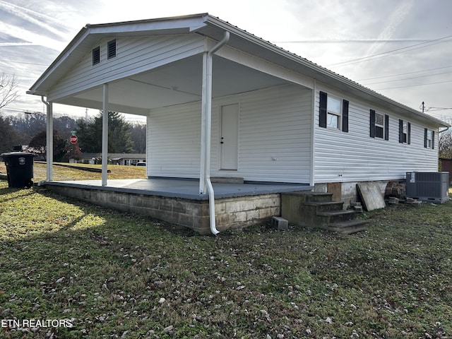 view of side of home featuring a lawn and central AC