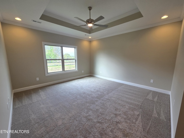 carpeted spare room with a tray ceiling, visible vents, ornamental molding, and ceiling fan