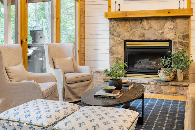 sitting room with a fireplace, hardwood / wood-style floors, and wood walls