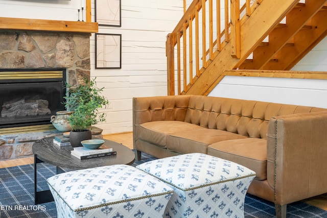 living room featuring a stone fireplace, wood walls, and hardwood / wood-style flooring