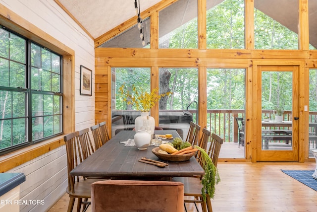 dining room with plenty of natural light, high vaulted ceiling, and light wood-type flooring