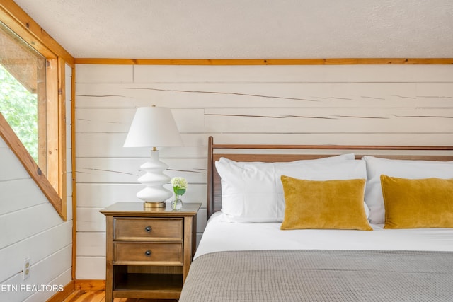 bedroom featuring a textured ceiling and wooden walls