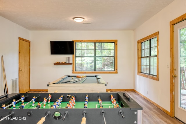 recreation room featuring hardwood / wood-style floors, a textured ceiling, and a wealth of natural light