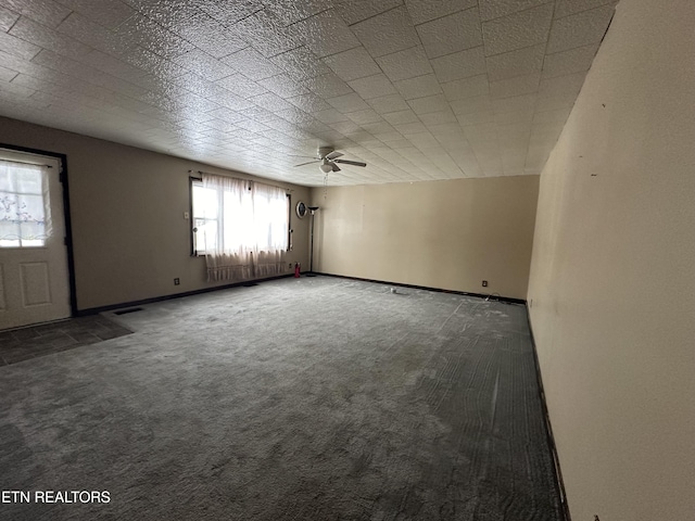 empty room featuring dark colored carpet and baseboards