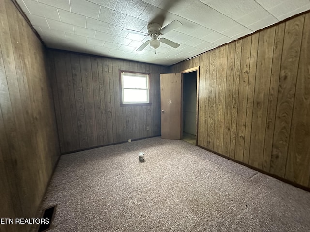 empty room with a ceiling fan and wood walls