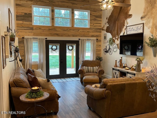 interior space featuring french doors, a towering ceiling, ceiling fan, and wood walls