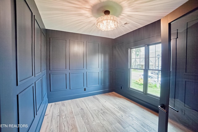 spare room with a chandelier and light hardwood / wood-style floors