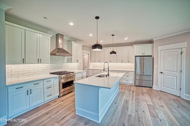 kitchen featuring white cabinets, sink, hanging light fixtures, wall chimney exhaust hood, and premium appliances