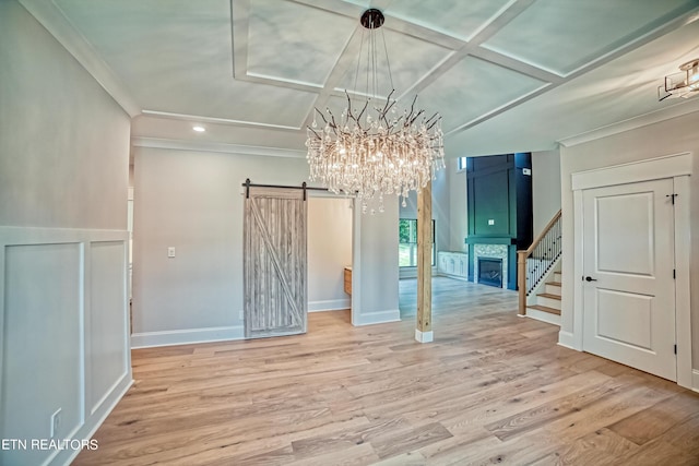 unfurnished dining area with coffered ceiling, an inviting chandelier, a barn door, crown molding, and hardwood / wood-style floors