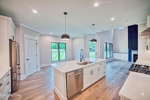 kitchen featuring a kitchen island with sink, sink, a fireplace, white cabinetry, and stainless steel appliances