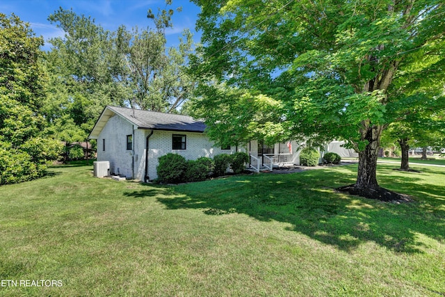 view of front of home featuring a front lawn, covered porch, and central AC unit