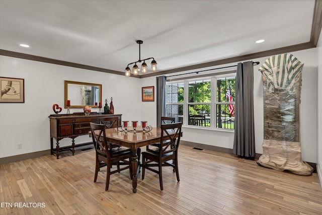 dining room with crown molding and light hardwood / wood-style floors