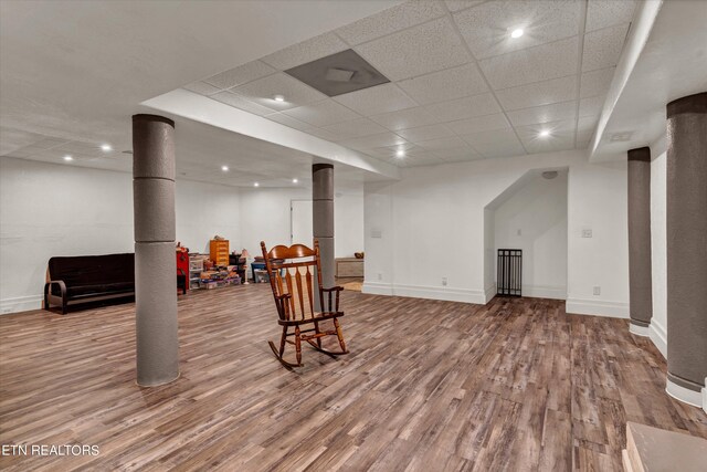 basement with a paneled ceiling and light wood-type flooring