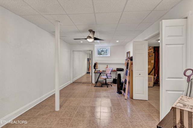 workout area featuring ceiling fan and a drop ceiling