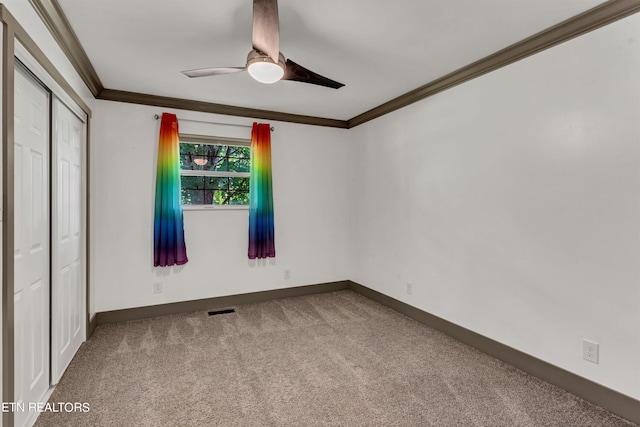 unfurnished bedroom featuring ceiling fan, carpet floors, crown molding, and a closet